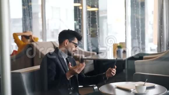 英俊的商人用智能手机和相机进行在线视频通话视频的预览图