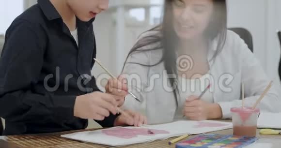 一个成熟的女人和她的儿子一起画一个学校项目的画像非常吸引人视频的预览图