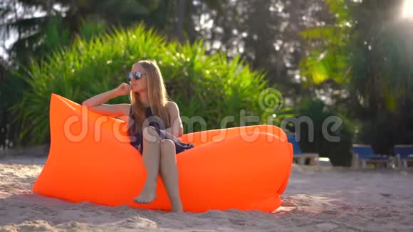 热带海滩上的年轻女子坐在充气沙发上暑假概念视频的预览图
