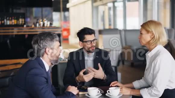 穿西装的胡子男在咖啡馆里在线付款然后和同事交谈视频的预览图