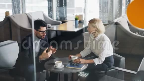 商业伙伴一男一女分享咖啡屋里的新闻视频的预览图