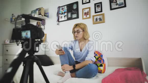 有魅力的女性知名博主正在使用相机为她的在线vlog录制视频她用手机说话视频的预览图