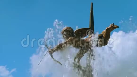 城市喷泉中的丘比特青铜雕塑被蓝色天空背景上的溅起的水花冲刷视频的预览图