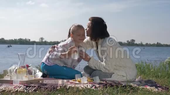 快乐的家庭假期年轻女性和小女孩的肖像在附近的草地上休息时喝柠檬水视频的预览图