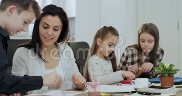 三个孩子放学后在一张大桌子上的客厅里做作业他们的成熟和成熟视频的预览图