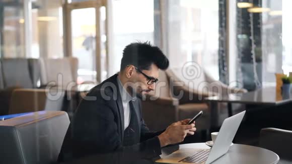 咖啡休息时戴着智能手机戴眼镜的自信胡子男人视频的预览图