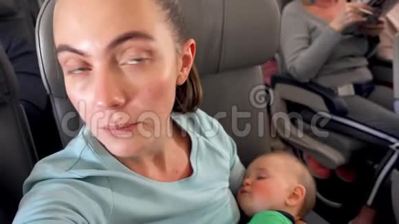 妈妈抱着熟睡的婴儿坐在飞机上视频的预览图