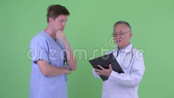 快乐成熟的日本男子医生和年轻男子病人一起听到好消息视频的预览图