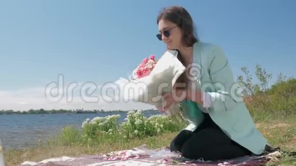花艺戴着眼镜的年轻花艺女孩把美丽的鲜花和包装纸做成一束鲜花视频的预览图