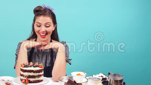 快乐的女孩糕点厨师坐在桌旁微笑着看着相机视频的预览图