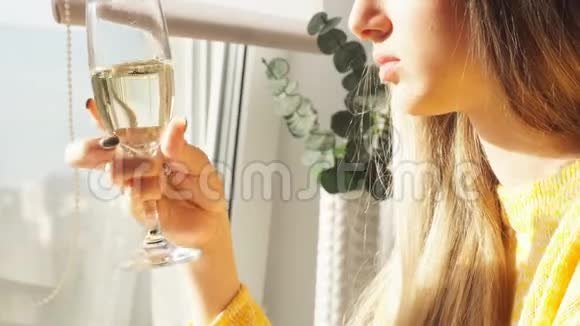 小女孩坐在靠近窗户的酒吧凳子上喝香槟视频的预览图