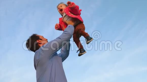 爸爸把一个快乐的孩子扔进了蓝天爸爸和他的小女儿在公园里玩幸福家庭的概念视频的预览图