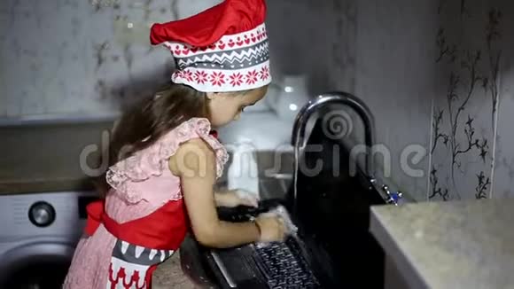 小女孩在厨房的水槽里洗手提电脑穿着红色围裙视频的预览图