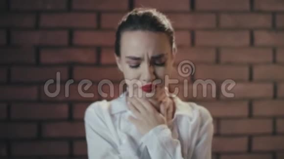 不高兴的女人在砖墙上感到喉咙痛和咳嗽视频的预览图