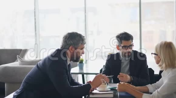 商务团队中老年男性和老年女性在咖啡馆里谈论咖啡视频的预览图