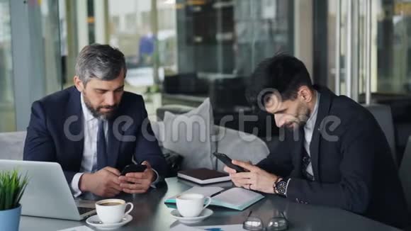在咖啡馆里男性同事用智能手机触摸屏幕会议视频的预览图