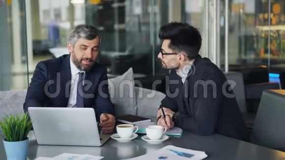 西装革履的同事在商务午餐时用手提电脑在咖啡馆聊天视频的预览图