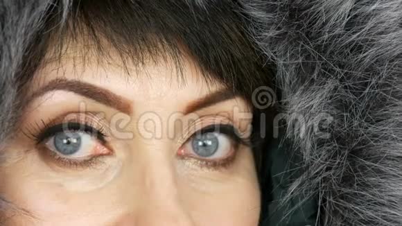 成年中年妇女美丽的蓝色大眼睛明亮的妆容彩绘箭头和假睫毛在人造毛皮视频的预览图
