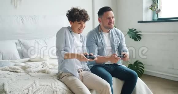 女孩和男孩夫妇坐在公寓里玩电子游戏玩得开心视频的预览图