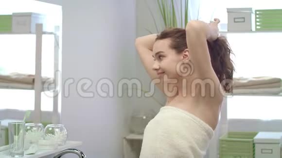 穿着浴巾微笑的女人在浴室做发尾镜视频的预览图