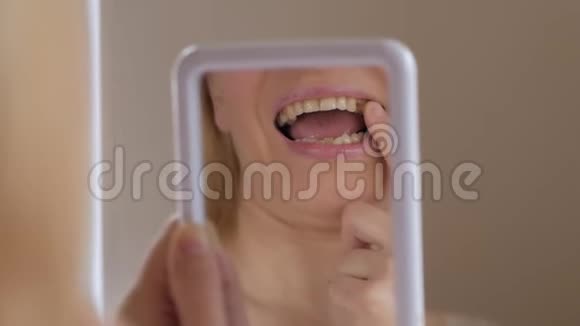在镜子里检查的一名成年妇女的面部特写嘴里缺了一颗牙齿视频的预览图