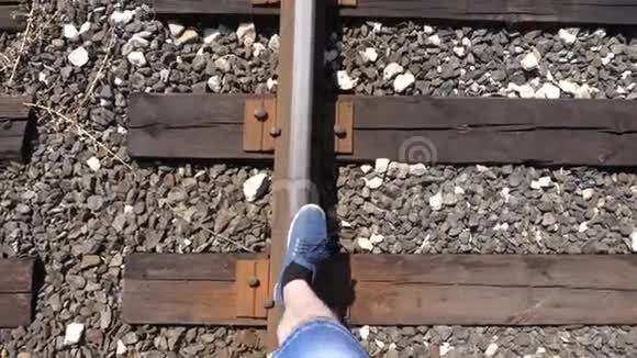 旅行者的腿在铁路上铁轨上行驶特写镜头游客踩着枕木1乘客落在后面视频的预览图