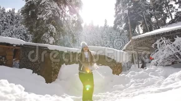 快乐的女孩在森林里的木屋附近享受一个寒冷阳光的冬日视频的预览图
