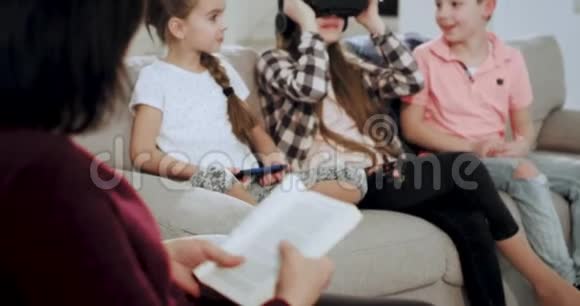当祖母阅读一本书时三个孙子用虚拟现实眼镜探索虚拟现实视频的预览图