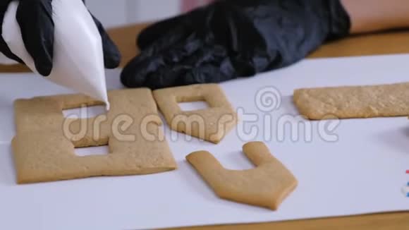 女人的手上装饰着糖甜的姜饼屋用的冰曲奇烹饪自制姜饼屋视频的预览图