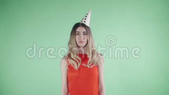 戴着派对帽的漂亮女孩站在绿色背景下的纸屑下视频的预览图