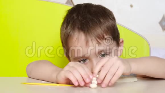 一个学龄前儿童坐在桌子旁用橡皮泥雕刻一个图形教育创造力和儿童视频的预览图