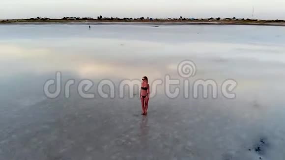一个穿着黑色泳衣的女孩站在水里看着夕阳视频的预览图