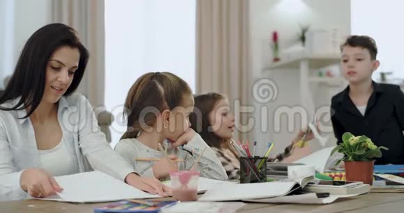在宽敞的客厅里一位母亲带着三个孩子一起做学校项目就像一个友好的团队他们度过了一个美好的时光视频的预览图