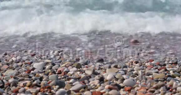 海滩上的鹅卵石和滚滚的绿松石海浪飞溅视频的预览图