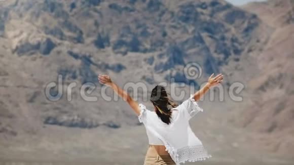 镜头跟随年轻快乐的自由女人跳跃和旋转手臂张开飞扬的头发微笑着在盐漠湖视频的预览图