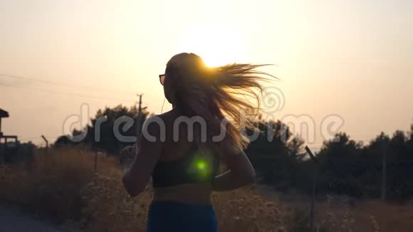 跟随运动女孩在乡间小路上慢跑戴墨镜的年轻女子在户外跑步听音乐视频的预览图