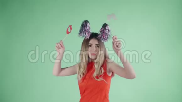 戴着派对帽的漂亮女孩正在绿色背景下飘落的纸屑和气球下跳舞视频的预览图