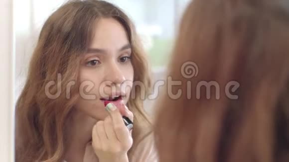 漂亮的女人用口红做唇妆在家里做浴室镜子视频的预览图