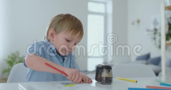 一个4岁的男孩坐在客厅的桌子旁在纸上画彩色铅笔视频的预览图