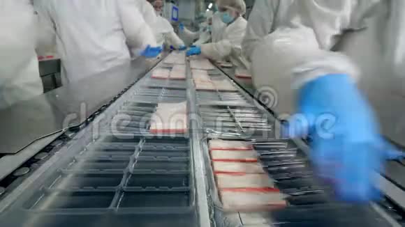 塑料盘子里装满了聚乙烯中的螃蟹棒工厂工人穿着防护服包装食品视频的预览图