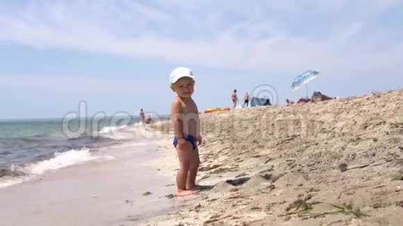 可爱的小男孩看着相机在海滩上微笑视频的预览图
