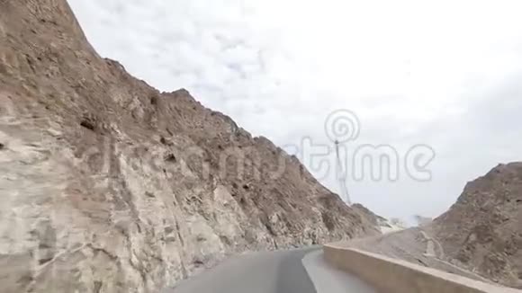 这辆车沿着一条狂野的道路在阿曼的岩石之间行驶视频的预览图