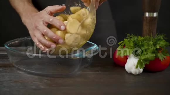 男人把土豆从碗里放进黑暗的厨房里的烤盘里视频的预览图