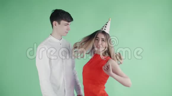 年轻的女人和男人在绿色的背景下在五颜六色的纸屑下跳舞视频的预览图