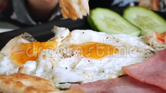 女人吃传统的英式早餐有煎鸡蛋烤面包火腿和培根特写视频的预览图