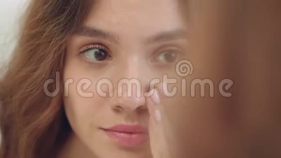 微笑的女人在面部皮肤前卫浴镜上涂抹保湿霜视频的预览图
