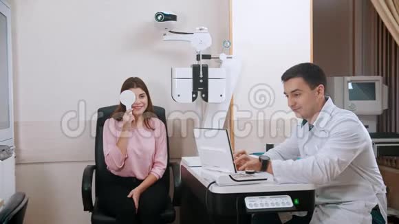 橱柜里的眼科治疗年轻女性检查她的视力用眼罩和视频的预览图