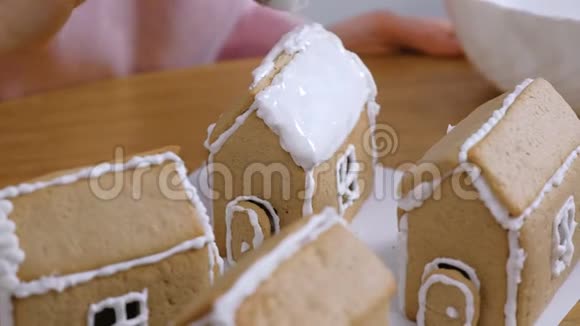 女人的手把姜饼屋的屋顶抹上糖霜烹饪自制姜饼屋视频的预览图