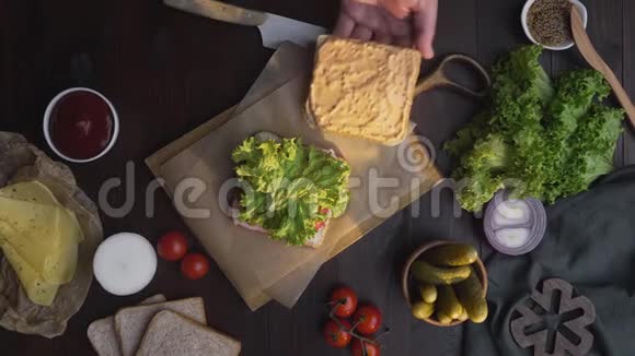 三明治与火腿和沙拉平躺在木板上在光线下厨师的手完成三明治视频的预览图