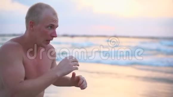 年轻的肌肉男在海边练习拳击男运动员在附近独自练习自卫视频的预览图